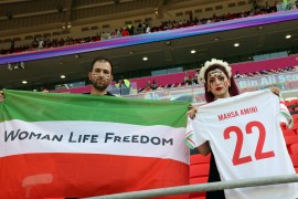 Ahead of a World Cup match against Wales on November 25, an Iranian fan holds up a flag emblazoned with the slogan &#39;Woman, Life Freedom&#39; in solidarity with the protest movement in Iran, while another carries a jersey bearing the name of Mahsa Amini, the 22-year-old whose death in police custody helped spark the protests [Showkat Shafi/Al Jazeera]