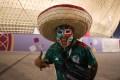 Fan wearing carnivalesque face mask in Mexico colours and a large sombrero