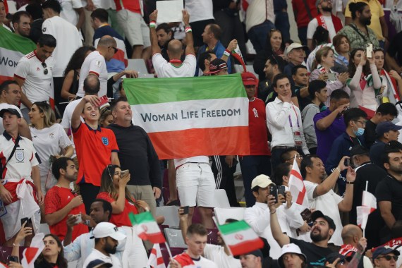 A man holds a "Woman Life Freedom" Iran flag.