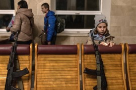 A child stands next to weapons placed on chairs as she waits for an evacuation train heading to Kyiv from Kherson city [Roman Pilipey/EPA-EFE]