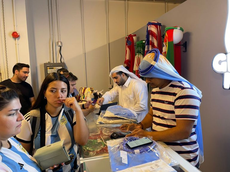 Arjantinli hayranlar spor aksesuarları almak için Doha'daki Ghutra Mundo mağazasından bekliyor 