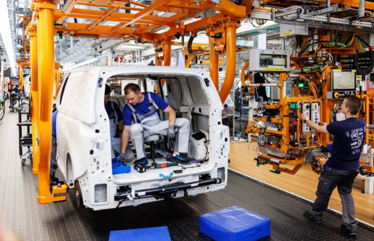 Mechanics work at the assembly line of the VW ID Buzz, the new all-electric microbus from Volkswagen Commercial Vehicles, at the Volkswagen plant in Hanover, northern Germany on June 16, 2022. - The company plans to produce 130,000 cars a year in Hanover.  (Photo by Axel Heimken/AFP)