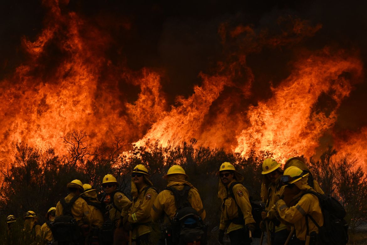 CalFire firefighters turn away from the fire to watch for any stray embers during the Fairview fire in California