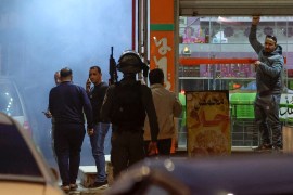A Palestinian man shuts his shop as Israeli security forces deploy in the occupied West Bank city of Huwara, after a Palestinian man was reportedly shot dead by Israeli police on December 2, 2022 [Jaafar Ashtiyeh/AFP]
