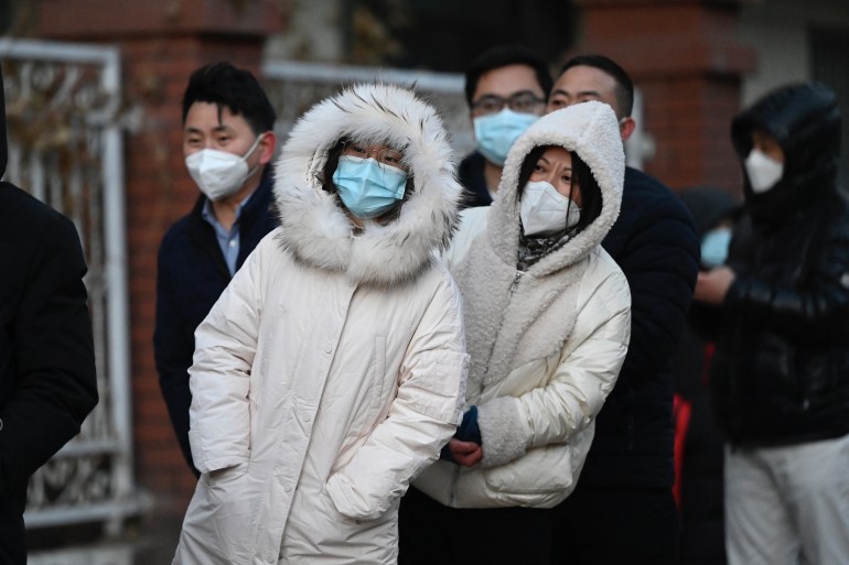 People in winter clothing wait in a long queue to be tested for COVID at an open nucleic acid testing site as many testing stations are shut down in Beijing on December 3, 2022.