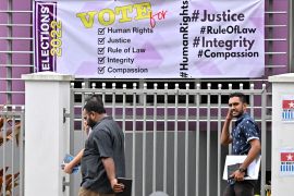 People walk past a banner ahead of Fijis general elections, in Suva