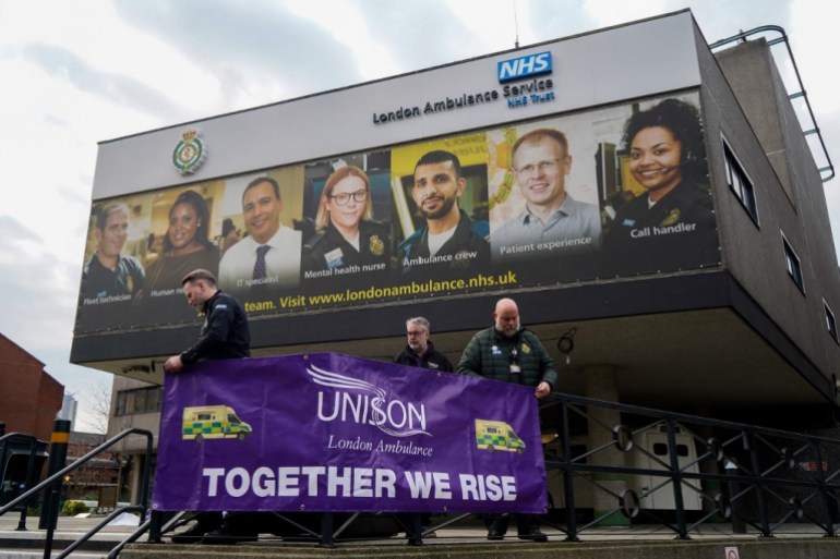 Members of staff place a banner on the railings outside the Waterloo ambulance station in London
