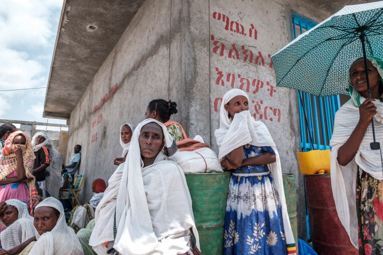 Women wait during a food distribution organised by the Amhara government near the village of Baker, 50 km southeast of Humera, in the Tigray Region of Ethiopia, on July 11, 2021. [Eduardo Soteras/AFP]