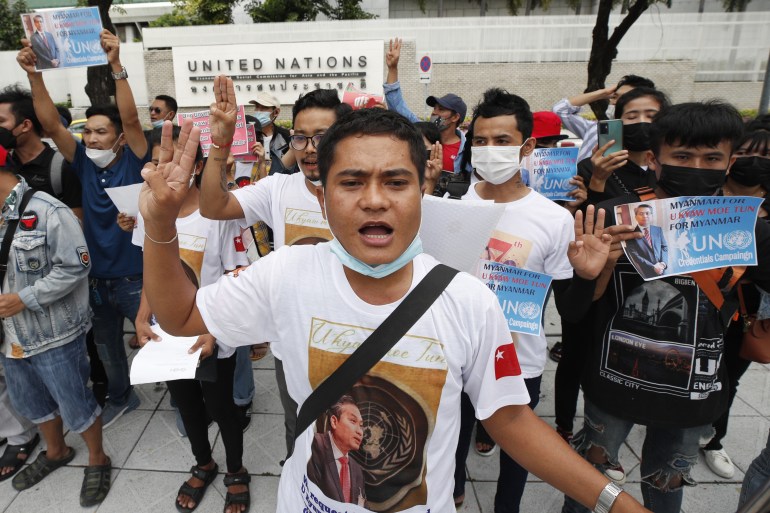 Manifestantes se reúnem do lado de fora da ONU em Bangkok em apoio a Kyaw Moe Tun.  Eles estão fazendo a saudação de três dedos e parecem determinados