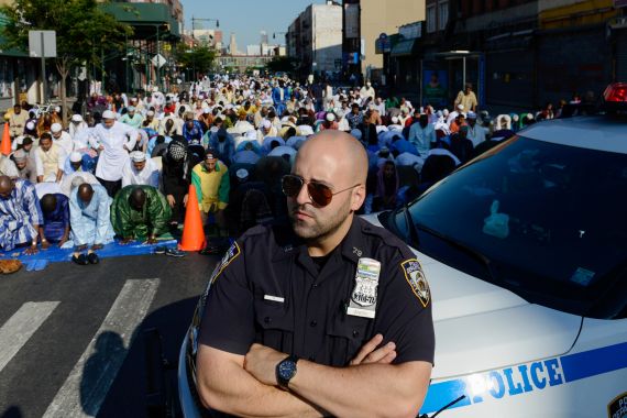 A New York City police officer stands guard as Muslims pray during the Eid holiday that marks the end of the Muslim holy month of Ramadan in the Brooklyn borough of New York City, July 6, 2016.