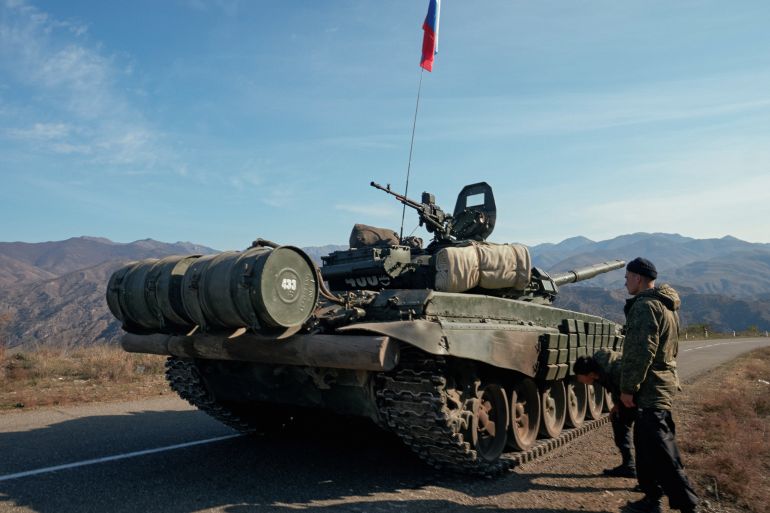 Service members of the Russian peacekeeping troops stand next to a tank near the border with Armenia in the region of Nagorno-Karabakh