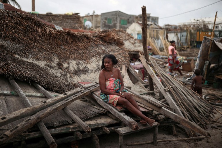 A woman sits on the debris of her destroyed house