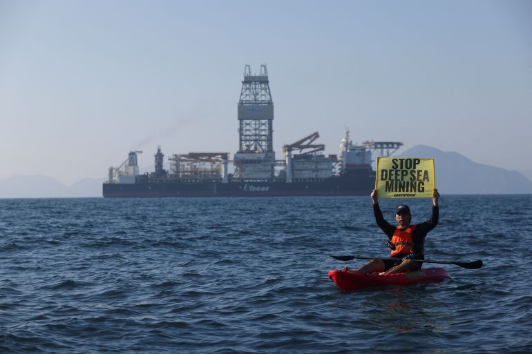 A Greenpeace activist holds a sign as he confronts the deep sea mining vessel Hidden Gem, commissioned by Canadian miner The Metals Company, as it returned to port from eight weeks of test mining in the Clarion-Clipperton Zone between Mexico and Hawaii, off the coast of Manzanillo, Mexico November 16, 2022.