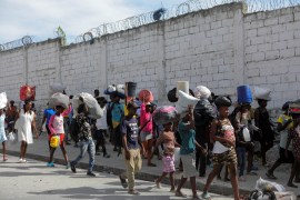 People displaced by gang warfare in Cite Soleil walk on a road near Port-au-Prince, Haiti [File: Ralph Tedy Erol/Reuters]