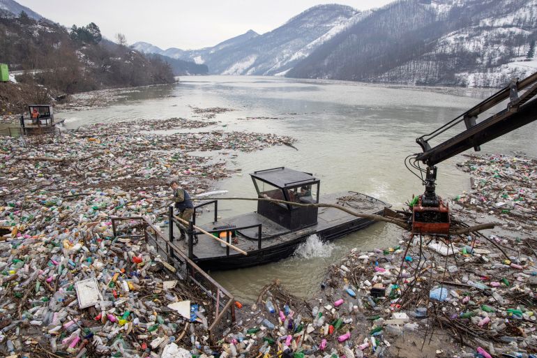 A worker collects plastic trash that litters the polluted Potpecko Lake near a dam's hydroelectric plant near the town of Priboj, Serbia