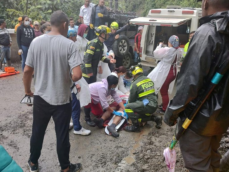 Police and rescue personnel secure a body recovered from a landslide