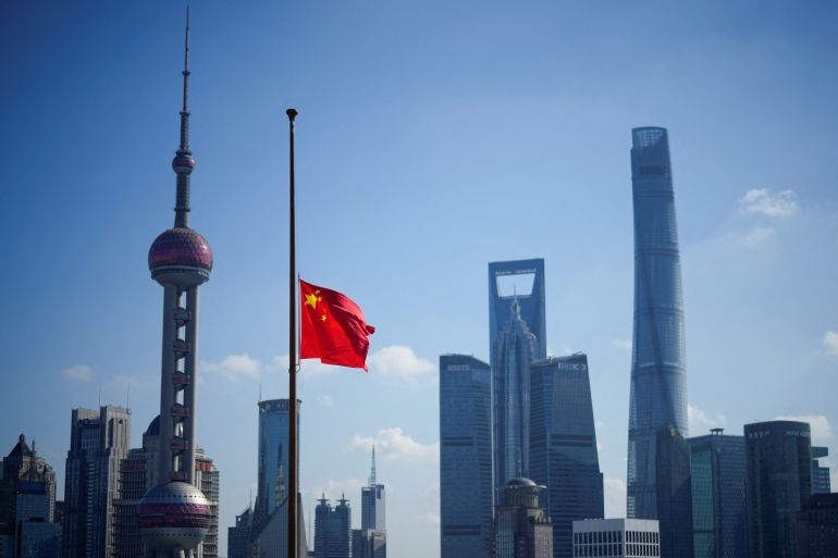 A Chinese flag at half mast against the Shanghai skyline.