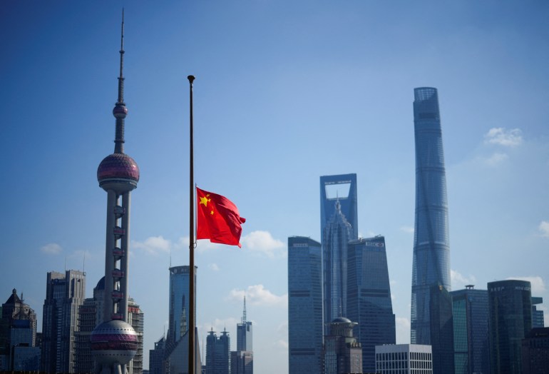A Chinese flag at half mast against the Shanghai skyline and a blue sky 