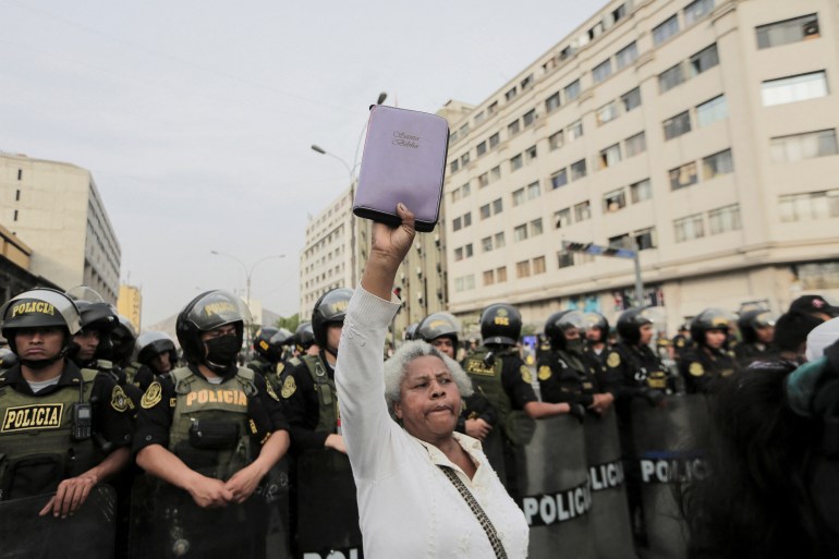 A demonstrator holds up a Bible in front of police officers as people demonstrate demanding presidential elections and the closure of Congress in Lima, Peru.