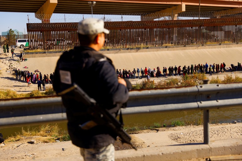 A soldier looks at the flow of people across the Rio Grande.