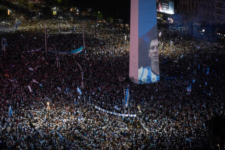 Soccer Football - FIFA World Cup Final Qatar 2022 - Fans in Buenos Aires - Buenos Aires, Argentina - December 18, 2022 Argentina fans celebrate winning the World Cup at the Obelisk with an image of Lionel Messi REUTERS/Mariana Nedelcu