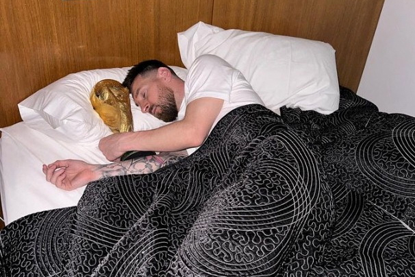 Argentina's Lionel Messi lies in bed with the FIFA World Cup trophy