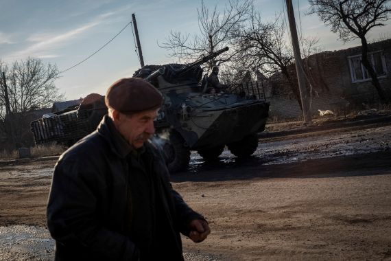 Los militares ucranianos viajan en un vehículo blindado de transporte de personal (APC), mientras un residente local camina por una calle vacía, en medio del ataque de Rusia a Ucrania, en Lyman, región de Donetsk, Ucrania, 20 de diciembre de 2022. REUTERS/Oleksandr Ratushniak