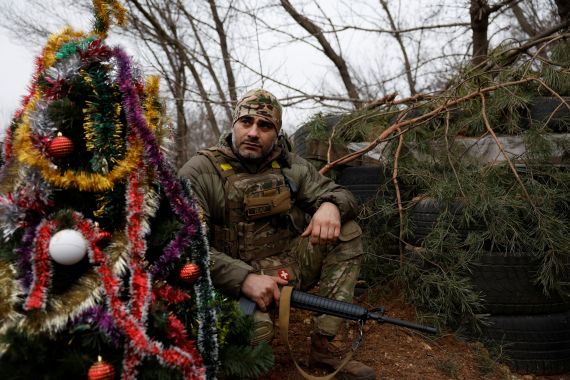 A Ukrainian serviceman with the Dnipro-1 Special Tasks Patrol Police regiment waits with his weapon beside a decorated Christmas tree in the trenches on the front line, as Russia's attack on Ukraine continues, on Christmas Eve in Bakhmut, Ukraine.