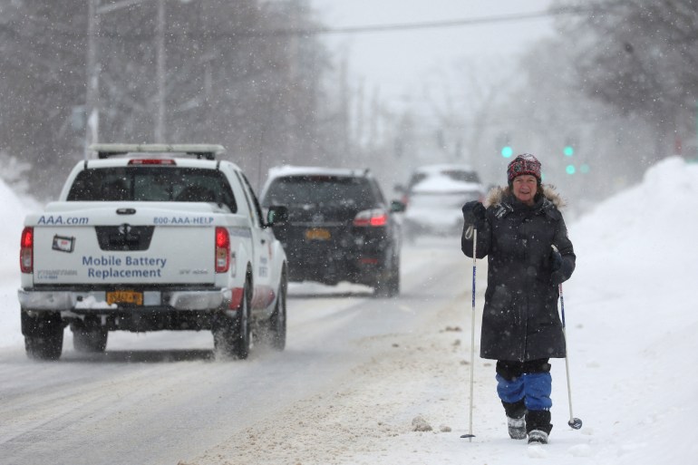 A woman walks as a car passes through a snowy New York state road