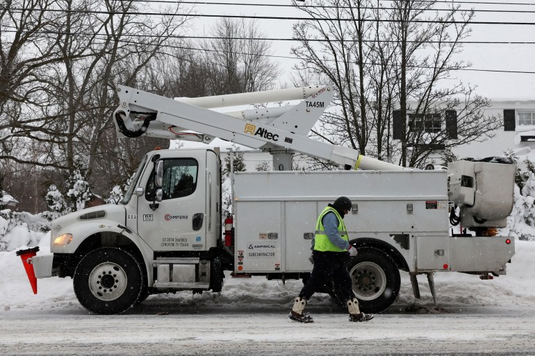 A utility worker walks past a truck after a winter storm in NY