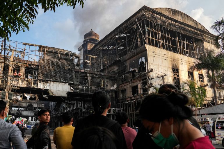 People gather in front of the Grand Diamond City hotel-casino, as Thai and Cambodian rescuers struggle to extricate dozens of people feared trapped after a fire broke, killing at least 10 and injuring dozens in Poipet near Thailand border, Cambodia