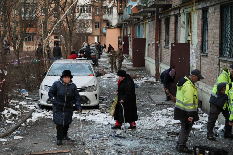 Local residents walk outside a building damaged during a Russian missile strike, amid Russia's attack on Ukraine.