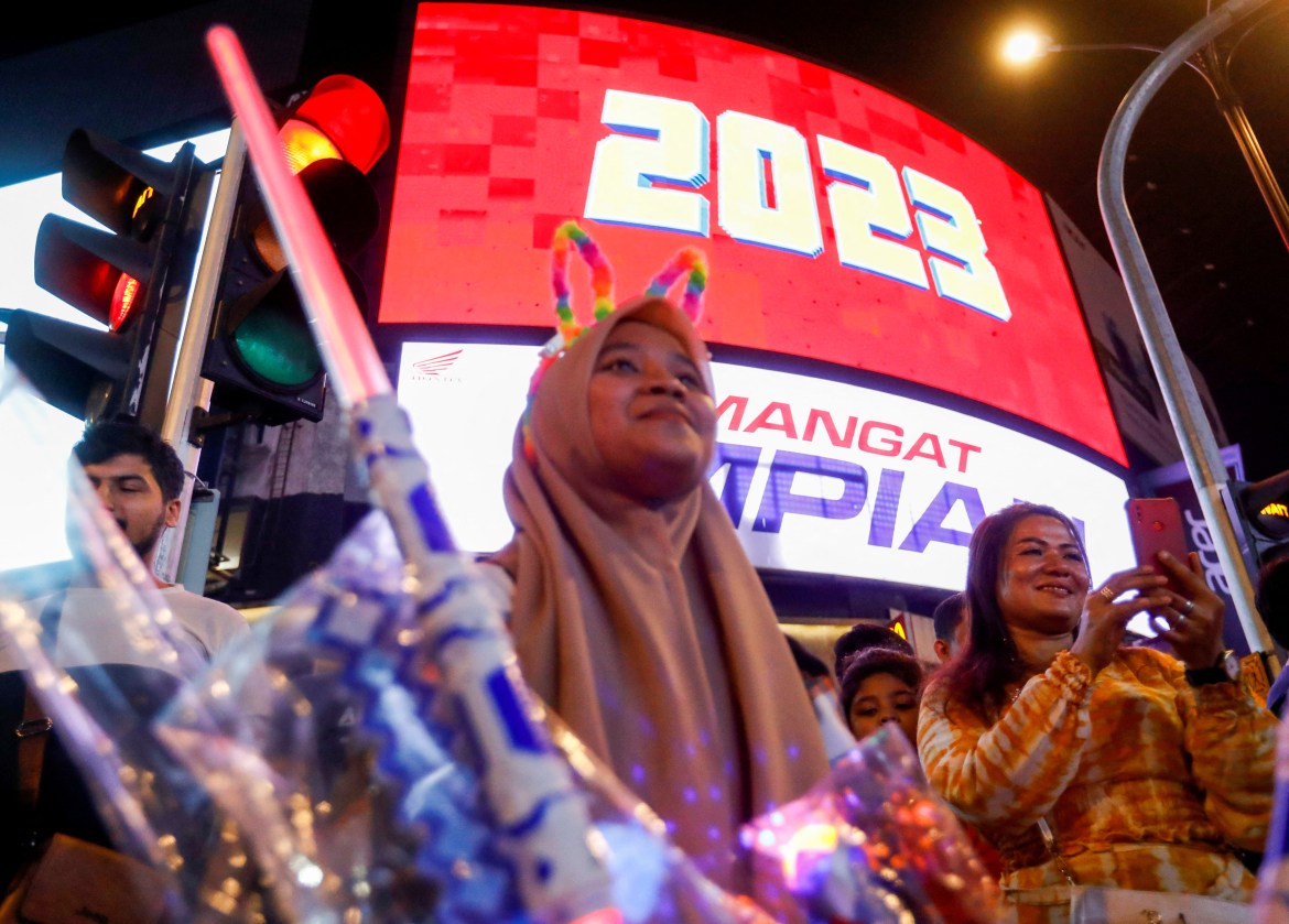 A screen displays the year 2023 as reavler celebrates New Year's Eve in Kuala Lumpur.
