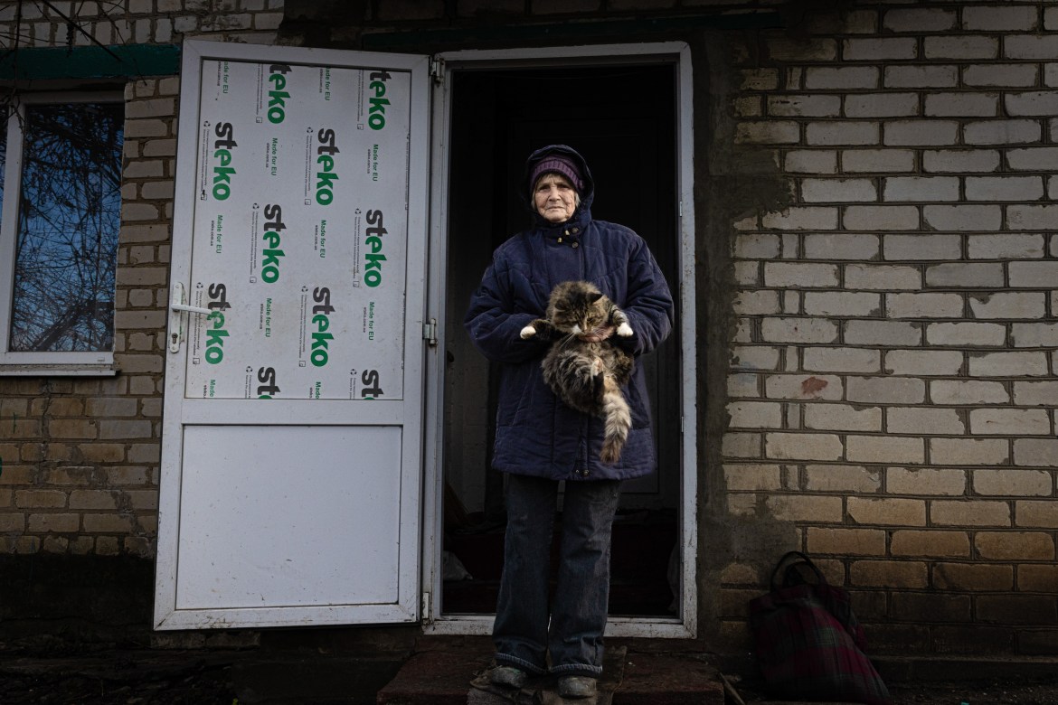 Woman holds her cat in front of her destroyed home