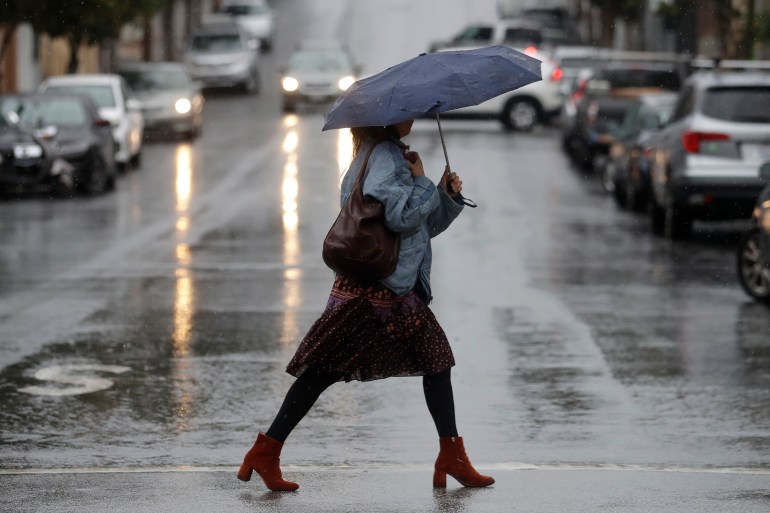 Une femme porte un parapluie en marchant sous la pluie à San Francisco