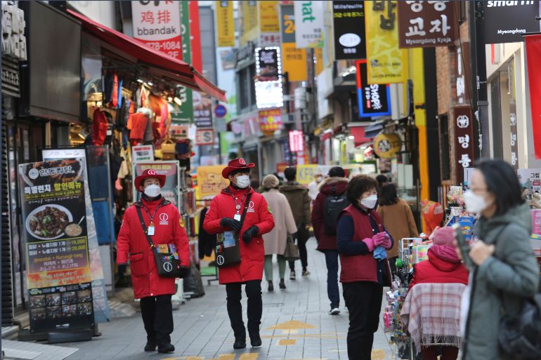 Tourist information helpers wearing face masks walk along a popular shopping street in Seoul, South Korea.