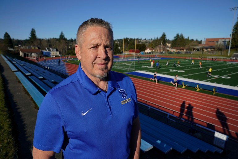 Former coach Joe Kennedy poses in the stands above the field at his old high school workplace