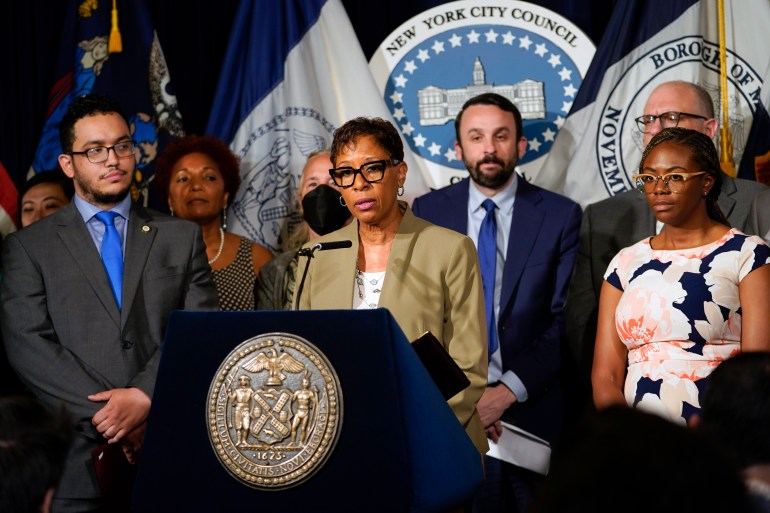 New York City Council Speaker Adrienne Adams stands at a podium, surrounded by colleagues