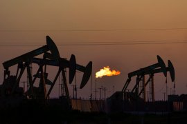 A flare burns off methane and other hydrocarbons as oil pumpjacks operate in the Permian Basin in Midland, Texas, last year [File: David Goldman/AP Photo]