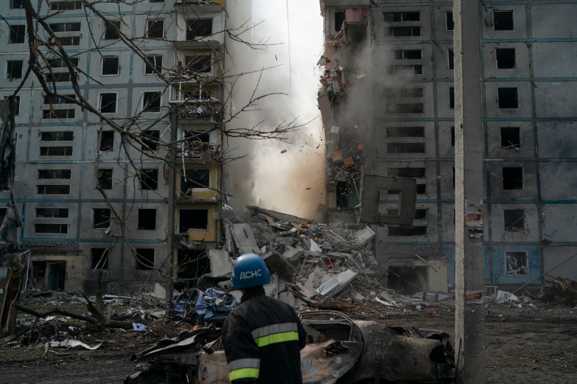 A firefighter looks at a part of a wall falling