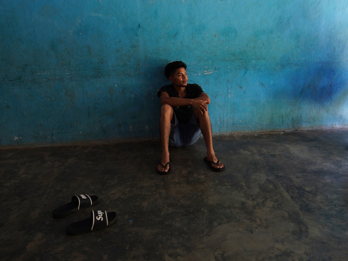 A migrant sits on the floor of a local's home where he is paying to stay