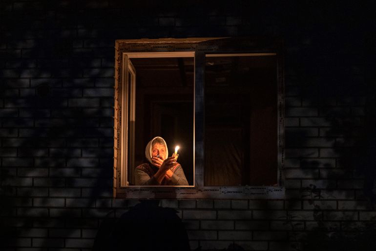 Catherine, 70, holds a candle in the window of her home during a power outage in Borodyanka, Kyiv region