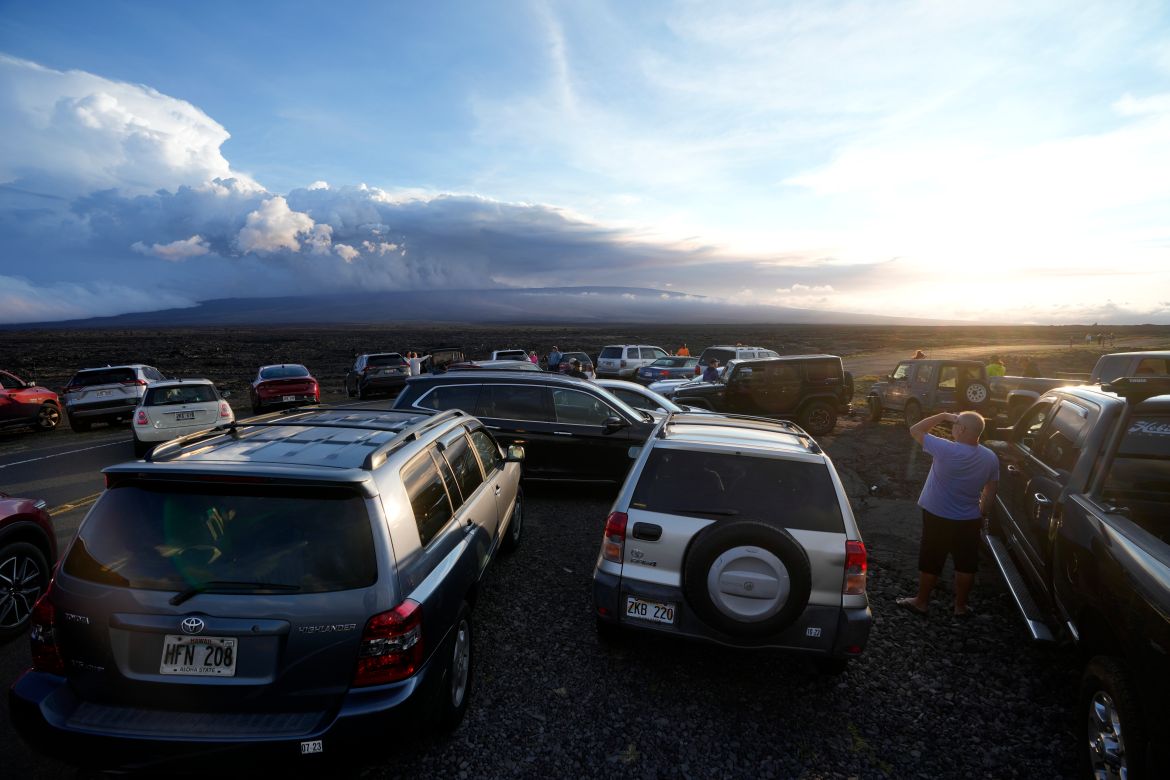 An overflow of cars sit in a parking lot near the Mauna Loa volcano