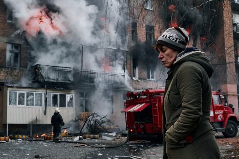 A local resident walks past her burning house after Russian shelling in Bakhmut