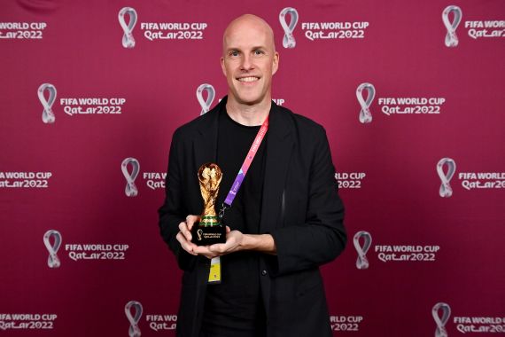 Grant Wahl smiles as he holds a World Cup replica trophy during an award ceremony in Doha, Qatar