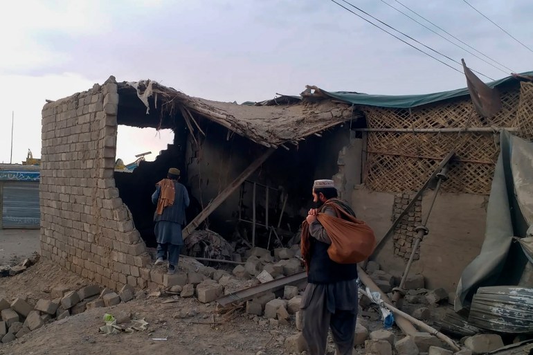 İnsanlar, Chaman'da Afgan güçlerinin bombardımanı nedeniyle hasar gören bir dükkana bakıyor.