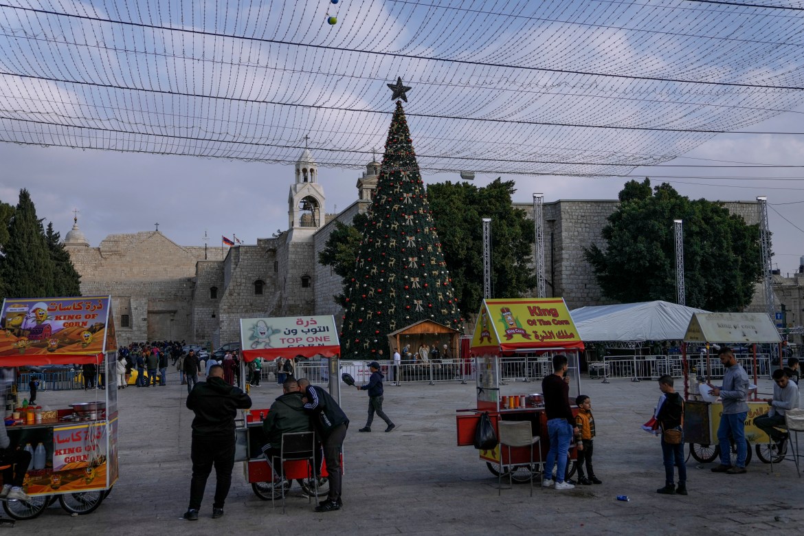 Palestinian vendors wait for clients next to the Christmas tree in Manger Square