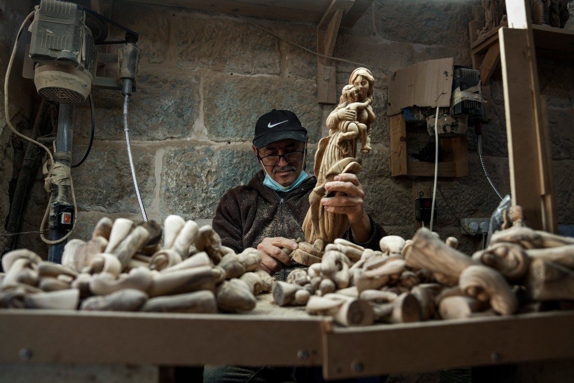 A Palestinian craftsman carves a figurine of the Virgin Mary