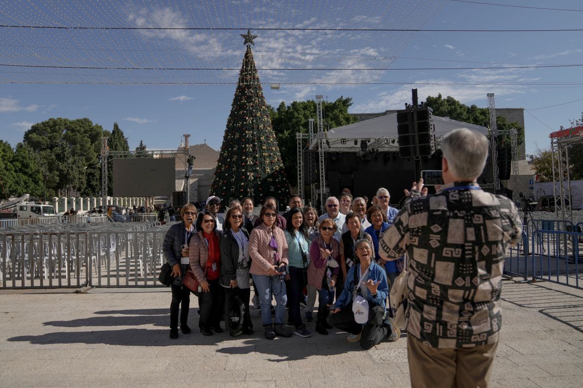 Tourists take pictures with the Christmas tree in Manger Square