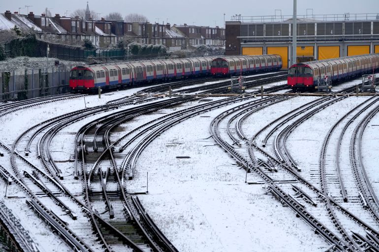 Snow covers the tracks as tube trains are parked in London